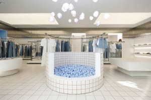 A modern retail interior featuring a ball pit and hanging cloud-shaped lights.