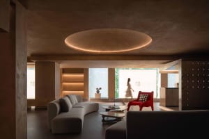 A modern interior design featuring a living room with concrete walls and a red accent chair.