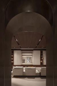 A modern living room featuring wood-paneled walls, upholstered furniture, and minimalist decor.