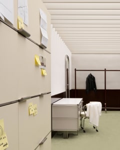 Modern minimalist office space featuring metal cabinets and plastic drawers, with a green carpet and white walls.