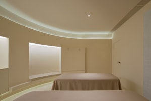 Modern minimalist bedroom with neutral tones, featuring two beds and minimalist furniture.