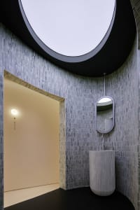 Modern bathroom design featuring marble tiles, sleek lines, and a curved ceiling with a circular skylight.
