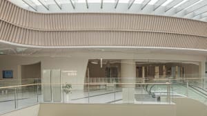 An interior view of a modern shopping center extension showcasing glass, concrete, and wooden architectural elements.