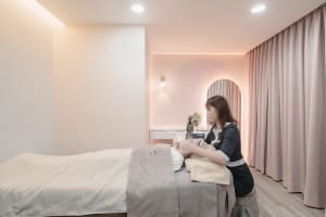 A serene spa room with neutral tones and soft lighting, featuring a massage bed and aesthetically pleasing decor.