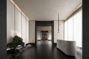A modern interior featuring a marble reception desk and a small bonsai tree with rocks and moss.