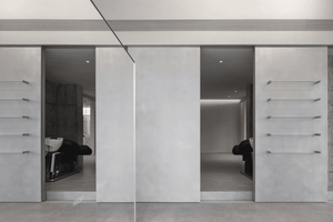 A modern spa interior with a minimalist design featuring a concrete wall and sleek black furniture.