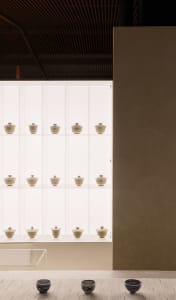 A collection of ceramic teacups displayed on shelves, with a few teacups arranged on the floor in the foreground.