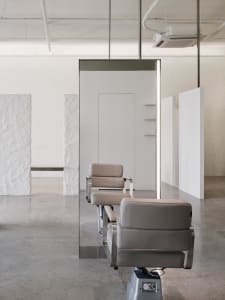 Modern spa interior with minimalist design featuring sleek, neutral-colored leather furniture and a large wall mirror.