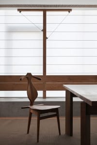 Minimalist interior design featuring a wooden table and simple chair with a wooden hanger.