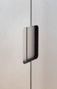 A minimalist metal handle mounted on a brushed aluminum surface.