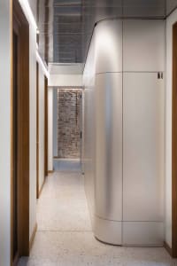 A minimalist office corridor features white panels on the walls and doors.