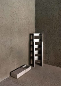 A modern, minimalist metal shelf against a textured gray wall.