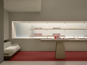 A modern retail storefront with minimalist design, white wooden shelves, and glass display cases.