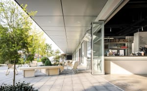 Modern exterior of a coffee shop with glass walls and seating area.