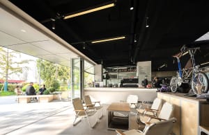 A modern, industrial-style coffee shop interior featuring metal-framed furniture, a concrete counter, and a relaxed seating a