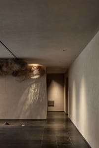 Fabric lighting fixture in a corridor with concrete walls and floor tiles.