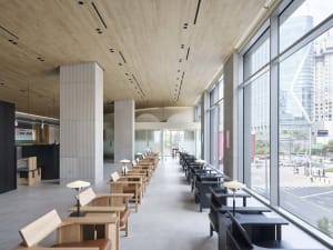Modern cafeteria interior with wooden seating, glass partitions, and concrete flooring.