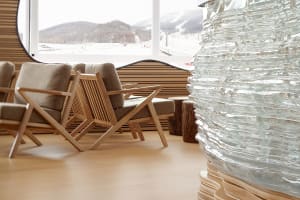 A modern living room featuring wooden furniture, a large glass window, and a textured glass sculpture.