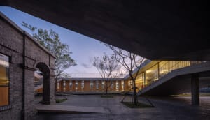 Contemporary interior space with wooden structures, glass walls, and a concrete ceiling.