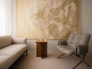 Minimalist living room with soft, comfortable furniture and a large, abstract wall art. The space features modern materials a