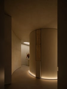 A modern corridor with curved concrete walls and illuminated floor edges.