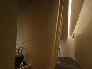 A minimalist corridor with wooden walls and a light source at the end.