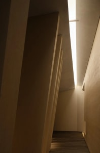 A modern interior space featuring a minimalist design with concrete walls and floor, illuminated by skylights.