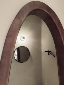 A modern interior design featuring a wooden framed arch-shaped mirror.