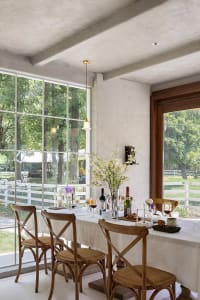 A modern dining room with wooden seating, large windows, and a table set for a meal.