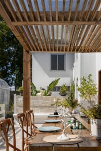 A minimalist outdoor dining space featuring wooden tables, glass decor, and concrete elements.