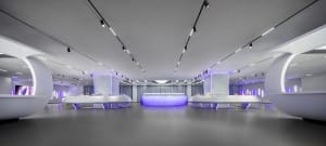A modern minimalist retail space featuring sleek white surfaces and purple lighting.