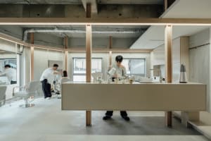 Person pouring coffee in a minimalist coffee shop with concrete kitchen counter