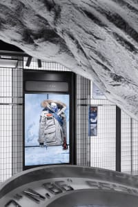 Modern retail storefront with duotone color scheme featuring a mannequin displaying a winter jacket with a fur-lined hood.