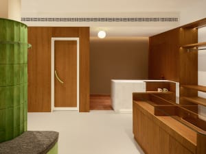 A modern retail storefront with wooden elements and a green cylindrical structure.