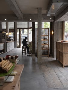 Interior of a coffee shop featuring concrete and wooden materials.