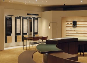 A modern shop with wooden furniture and display cases showcasing eyeglasses.