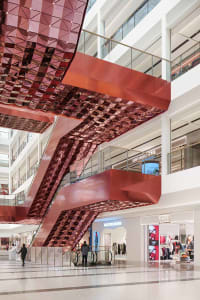 A shopping center interior with a modern design featuring metallic ceiling panels.