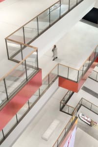 A modern shopping center interior featuring red accents on a white and gray floor.
