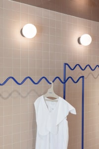 Modern industrial clothing display featuring a minimalist design with a white garment hanging on a metal hanger.