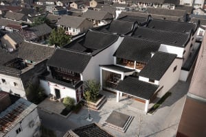 Aerial view of a traditional Chinese house with a clay-tile roof, white walls, and wooden beams.