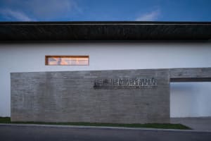 A minimalist bookstore with a concrete facade and wooden ceiling.