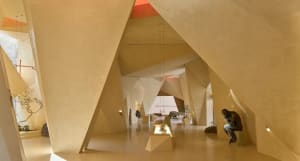 Modern art gallery space with angular architectural features and sandstone concrete walls