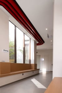 A modern interior design featuring a concrete corridor with red beams and large windows.