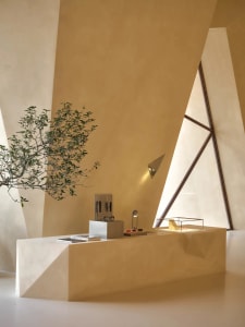 A modern office space with a concrete desk and plants, featuring geometric shapes and a triangular window.