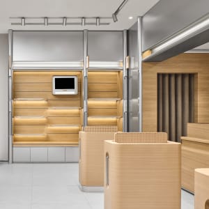 A modern retail shop interior featuring wooden shelves, metal railings, and a digital display.