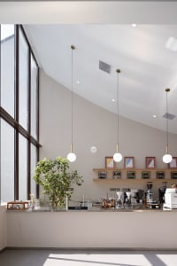 A minimalistic coffee shop interior featuring modern materials and ample natural lighting.
