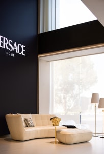 A modern living room with a white leather sofa, glass coffee table, and floor lamps.