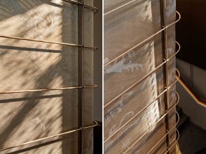 A modern interior with metallic textile blinds creating abstract patterns on the floor.