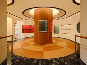 A modern retail shop interior with a central wooden pillar, glass display case, and black marble floor