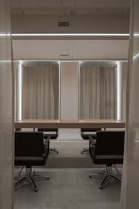 A modern hair salon station featuring a wooden countertop and glass panels.